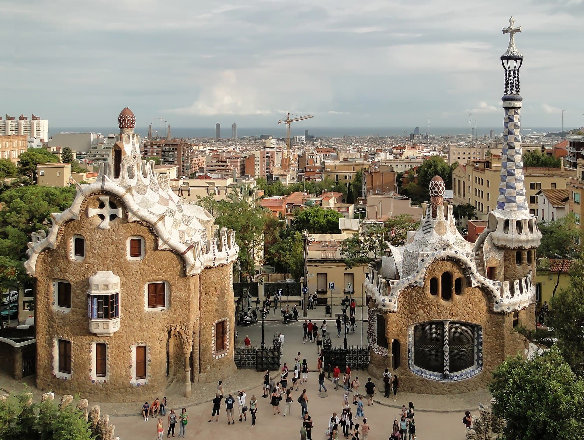 The mosaic gatehouses at Park Güell, with Barcelona and the sea beyond