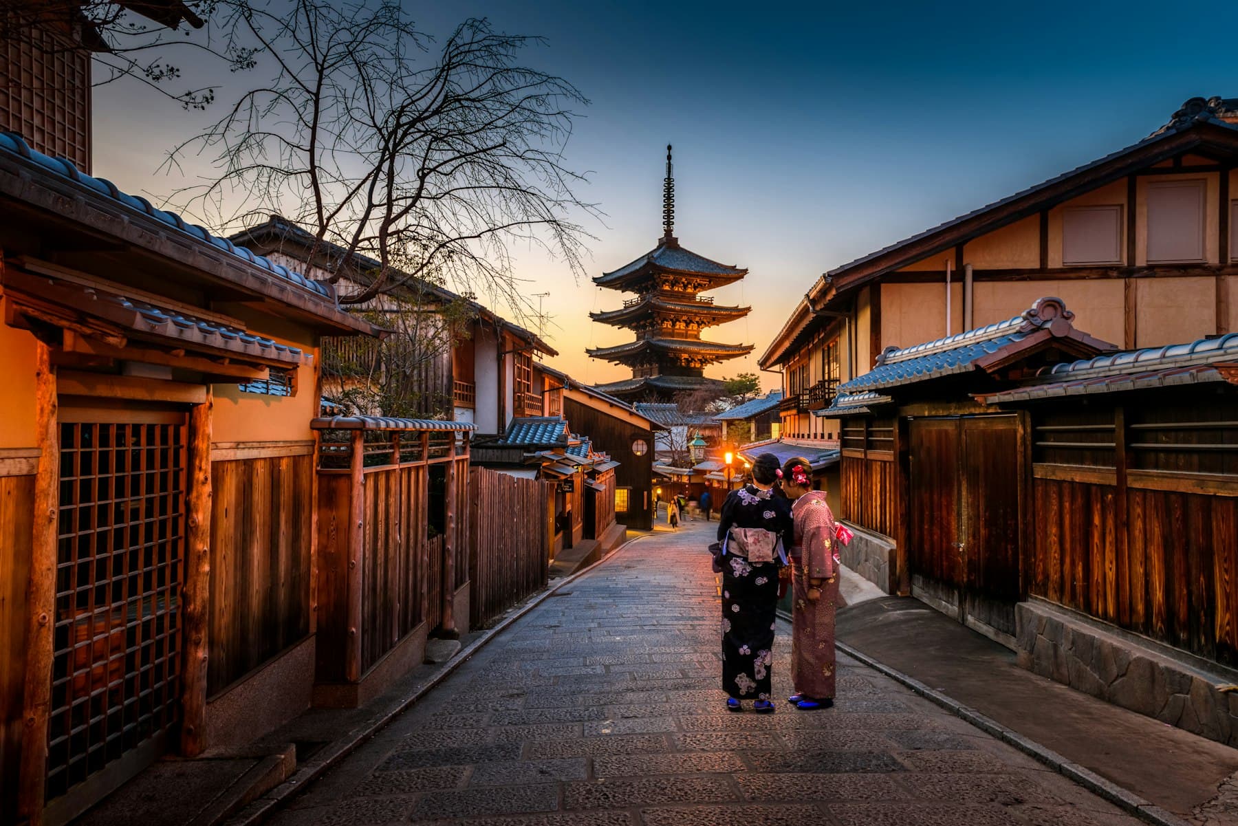 People in kimono on a Kyoto street at dusk, with a pagoda ahead