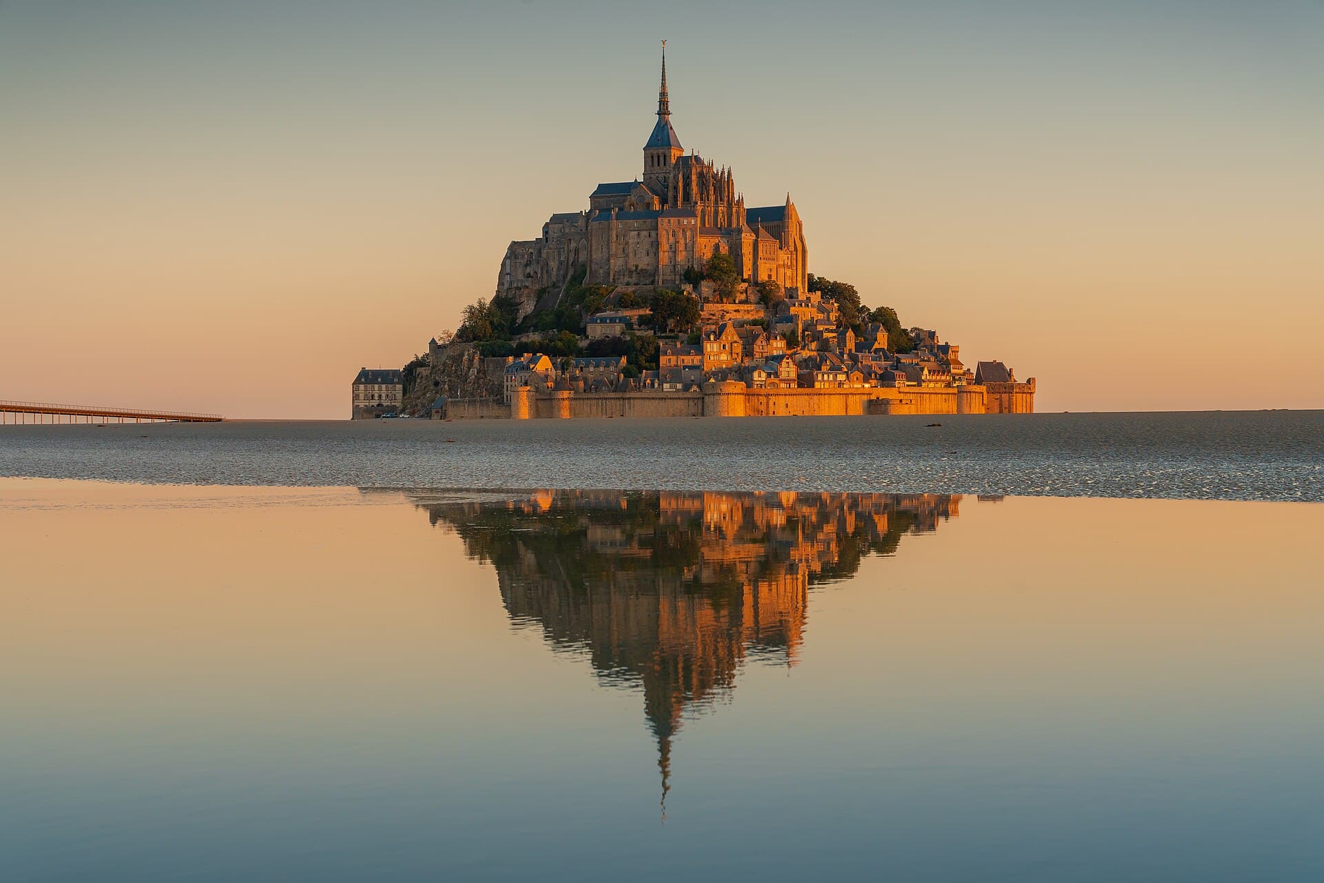 Mont-Saint-Michel at sunrise, with the causeway and the abbey reflected in the bay