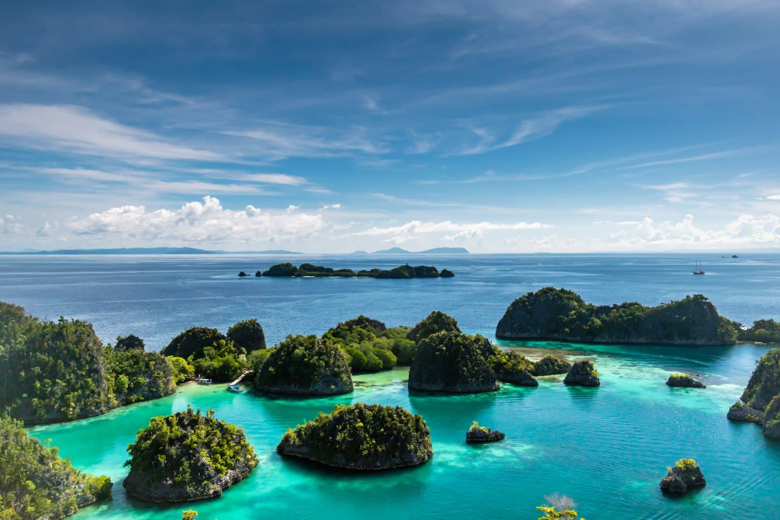 Forested limestone islands in turquoise water under a blue sky