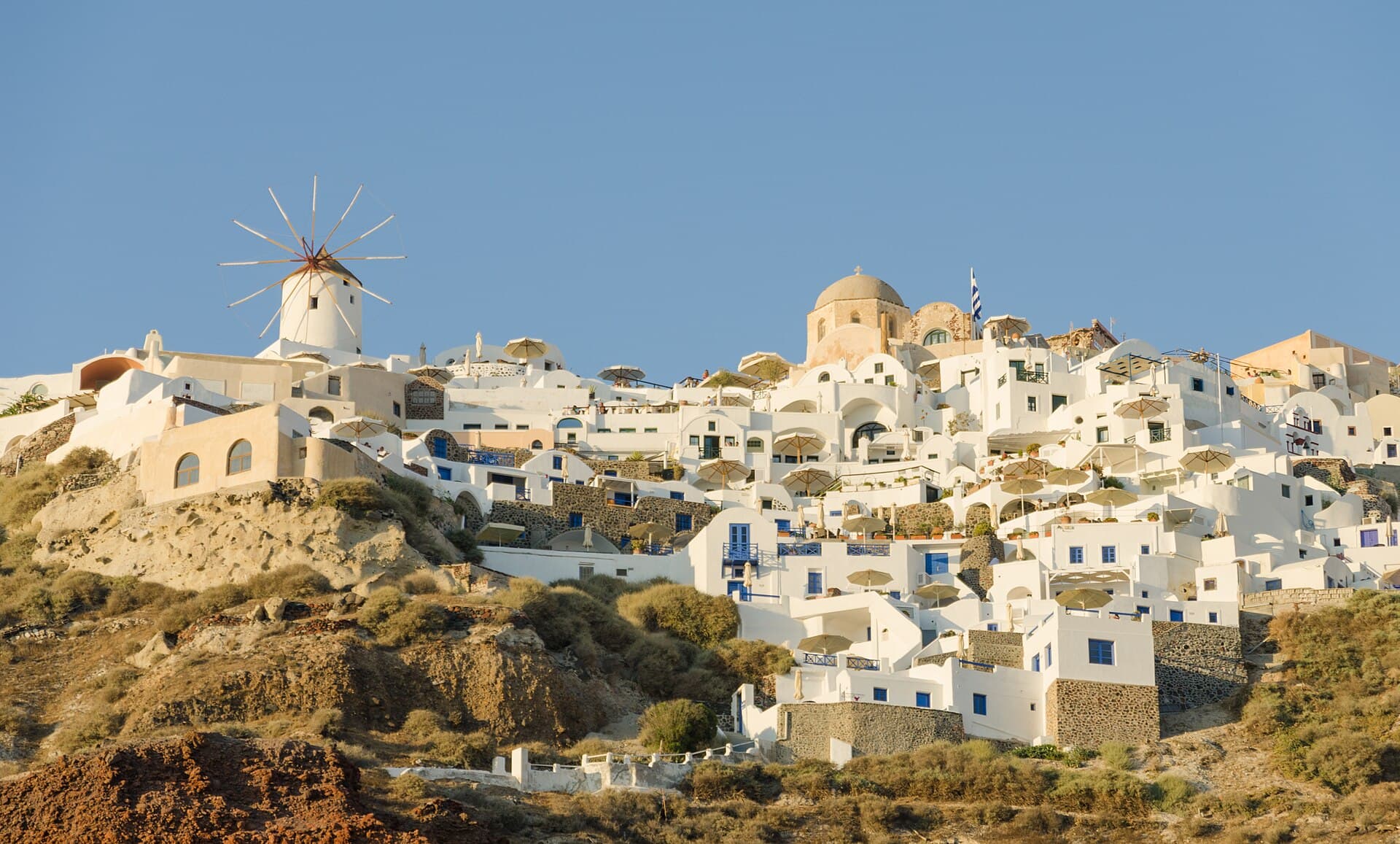 White houses, blue details, and a windmill on the cliff at Oia, Santorini